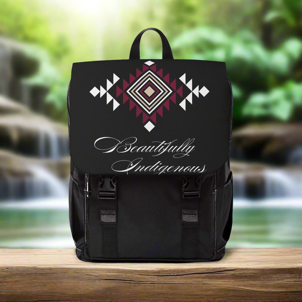 This black backpack features a beautiful burgundy, white, and beige tribal print pattern. Beautifully Indigenous printed across the bottom in cursive font.