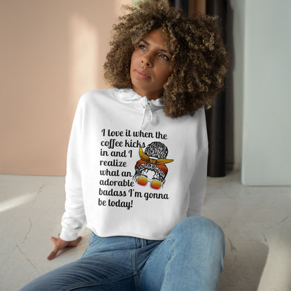 A stylish cropped hoodie printed with "I love it when the coffee kicks in and I realize what an adorable bad ass I'm gonna be today!" with a curly messy bun woman with orange glasses and knotted head band - white