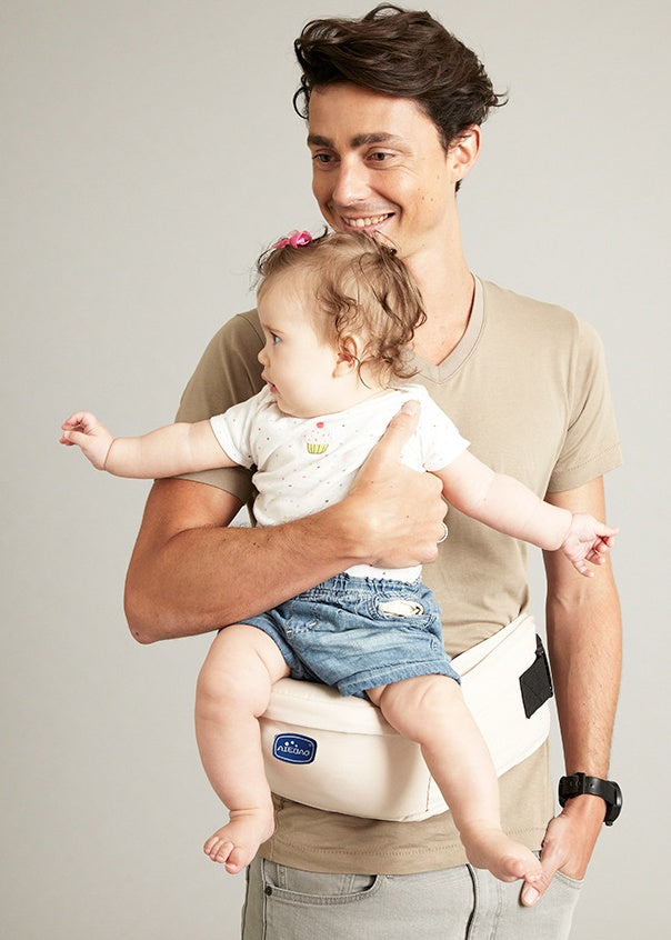 Dad carrying a baby with the baby hip carrier in creamy white. Clip this belt on and continue your day. Relieve back pain from holding your baby. For mom's, Dad's,  siblings, and anybody who wants hold an adorable baby. 