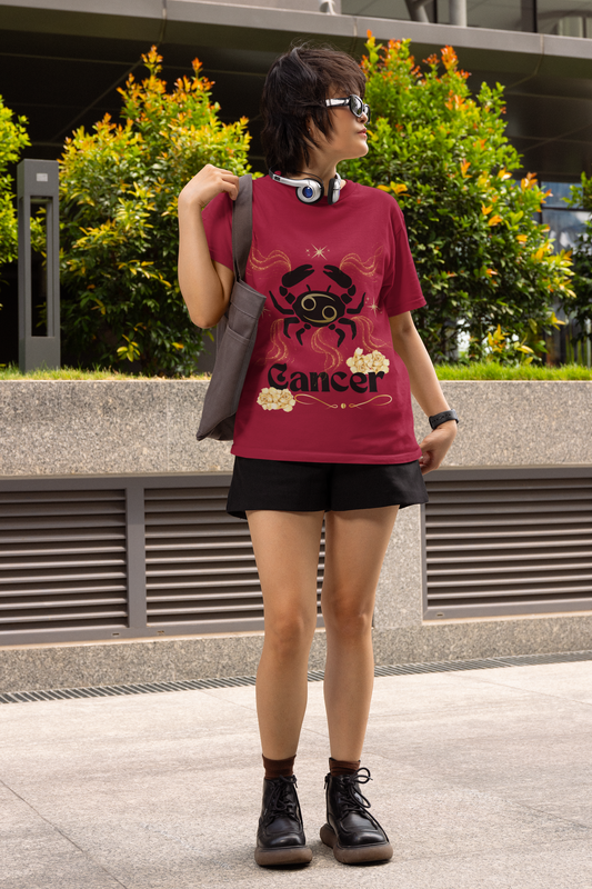 Black crab in the center with a gold Cancer symbol on its back surrounded by outward way gold glitter lines. Cancer printed across the bottom in bold black font with ivory gold roses above the top right corner of the word Cancer and below the left bottom corner. A gold abstract line underlines the word - printed on an antique cherry red shirt