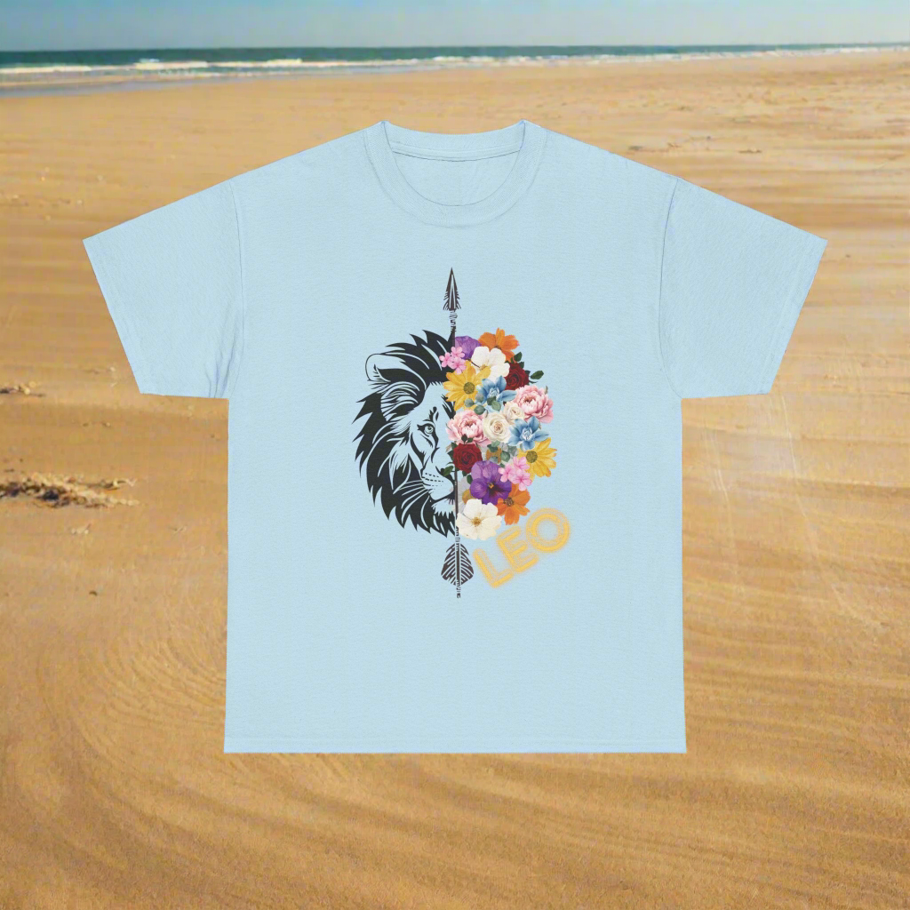 Leo Horoscope Tshirt. Half of a lions face cut down the middle by an arrow. The other half is a beautiful assortment of multicolored flowers with Leo printed in the corner in neon lit yellow font, printed on a light blue shirt.