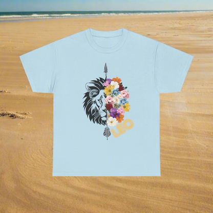 Leo Horoscope Tshirt. Half of a lions face cut down the middle by an arrow. The other half is a beautiful assortment of multicolored flowers with Leo printed in the corner in neon lit yellow font, printed on a light blue shirt.