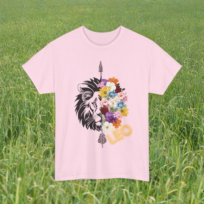 Leo Horoscope Tshirt. Half of a lions face cut down the middle by an arrow. The other half is a beautiful assortment of multicolored flowers with Leo printed in the corner in neon lit yellow font, printed on a light pink shirt.