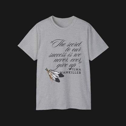 Native American Success Tshirt - Grey shirt quoting Wilma Mankiller stating the secret to our success is that we never ever give up. Eagle feathers in the corner tied together with leather string. 