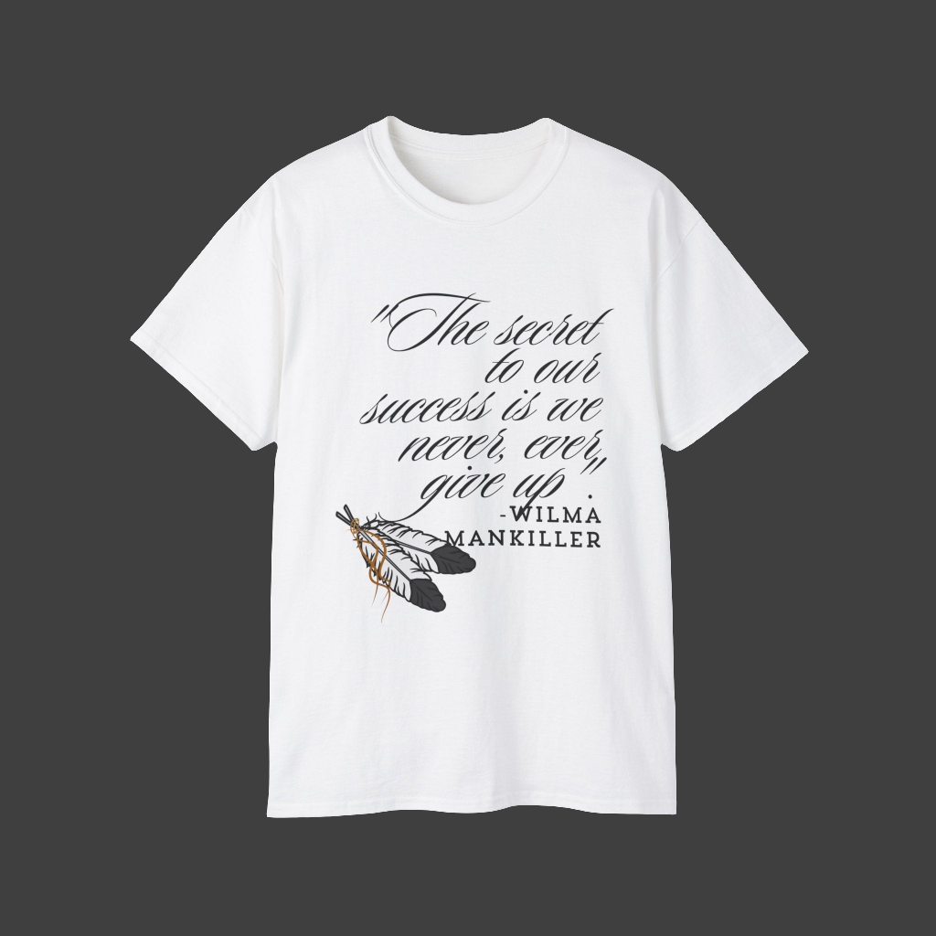 Native American Success Tshirt - White shirt quoting Wilma Mankiller stating the secret to our success is that we never ever give up. Eagle feathers in the corner tied together with leather string. 