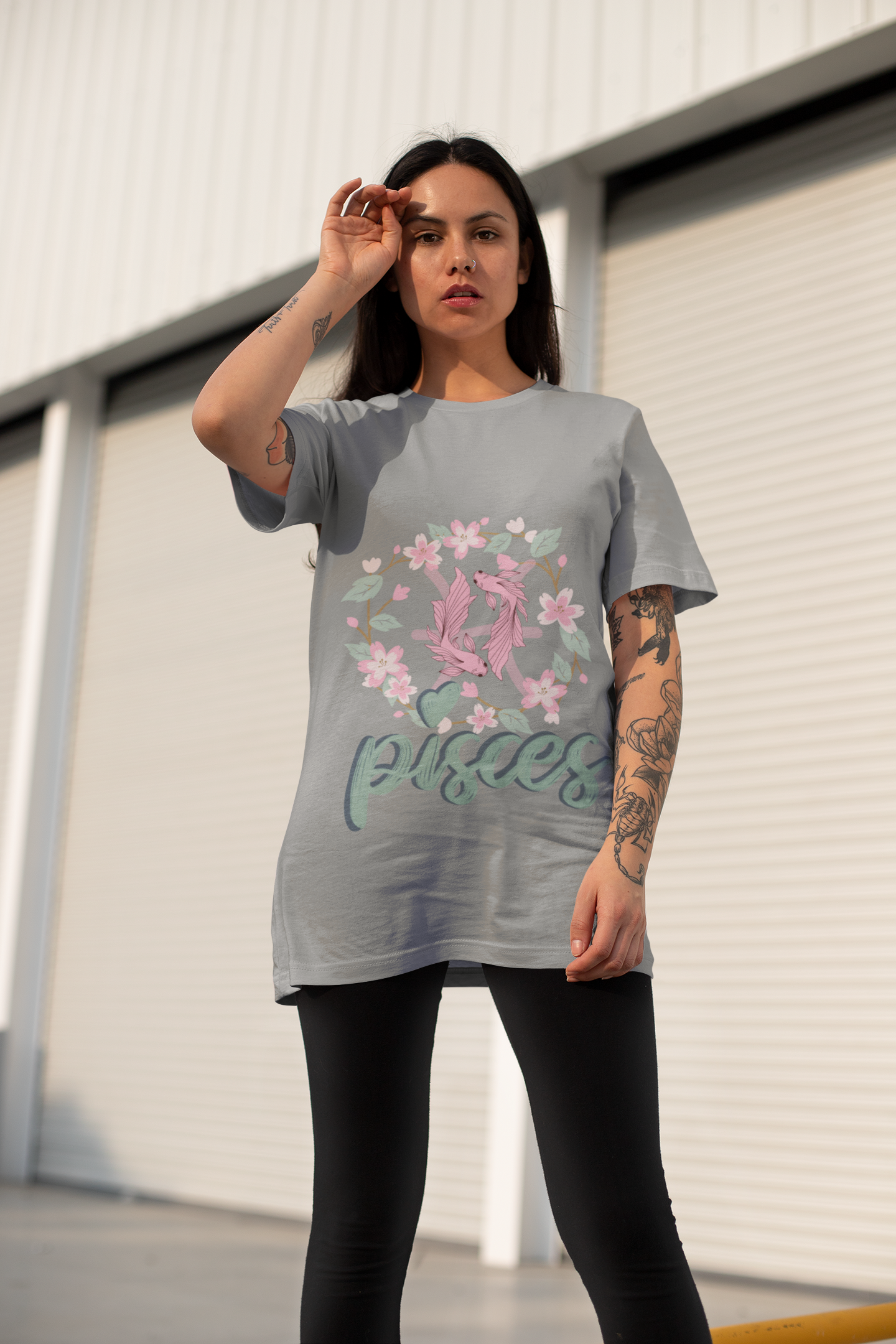 Pisces Horoscope Tshirt with 2 pink pisces fish surround with a light brown stem twisted into a circle with green leaves and pink flowers. Underneath Pisces is printed in light green font with navy blue shadow on an ash greyshirt