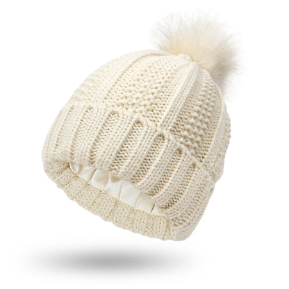 Pom Pom Beanie in beige with a knitted design and fur pom pom. This beanie is Satin Lined so say goodbye to frizzy beanie hair.