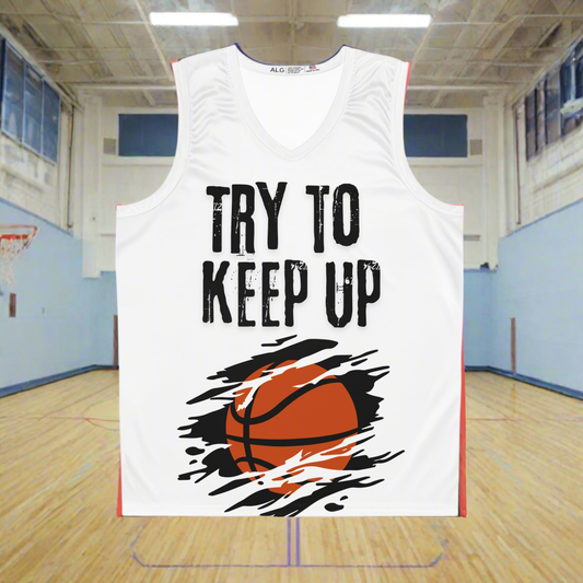 White basketball jersey with an orange basketball across the belly with a black background. Slash marks across the image. Try to keep up in large cracked font across the chest