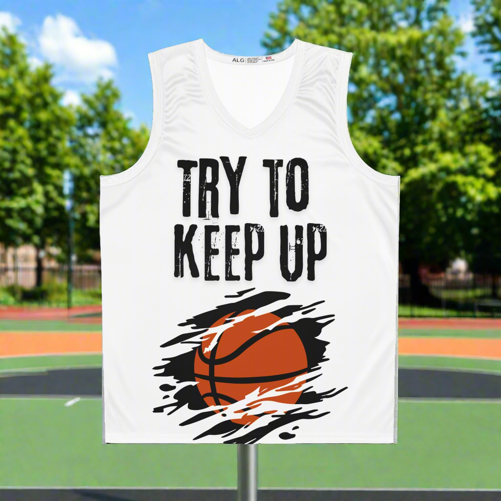 White basketball jersey with an orange basketball across the belly with a black background. Slash marks across the image. Try to keep up in large cracked font across the chest