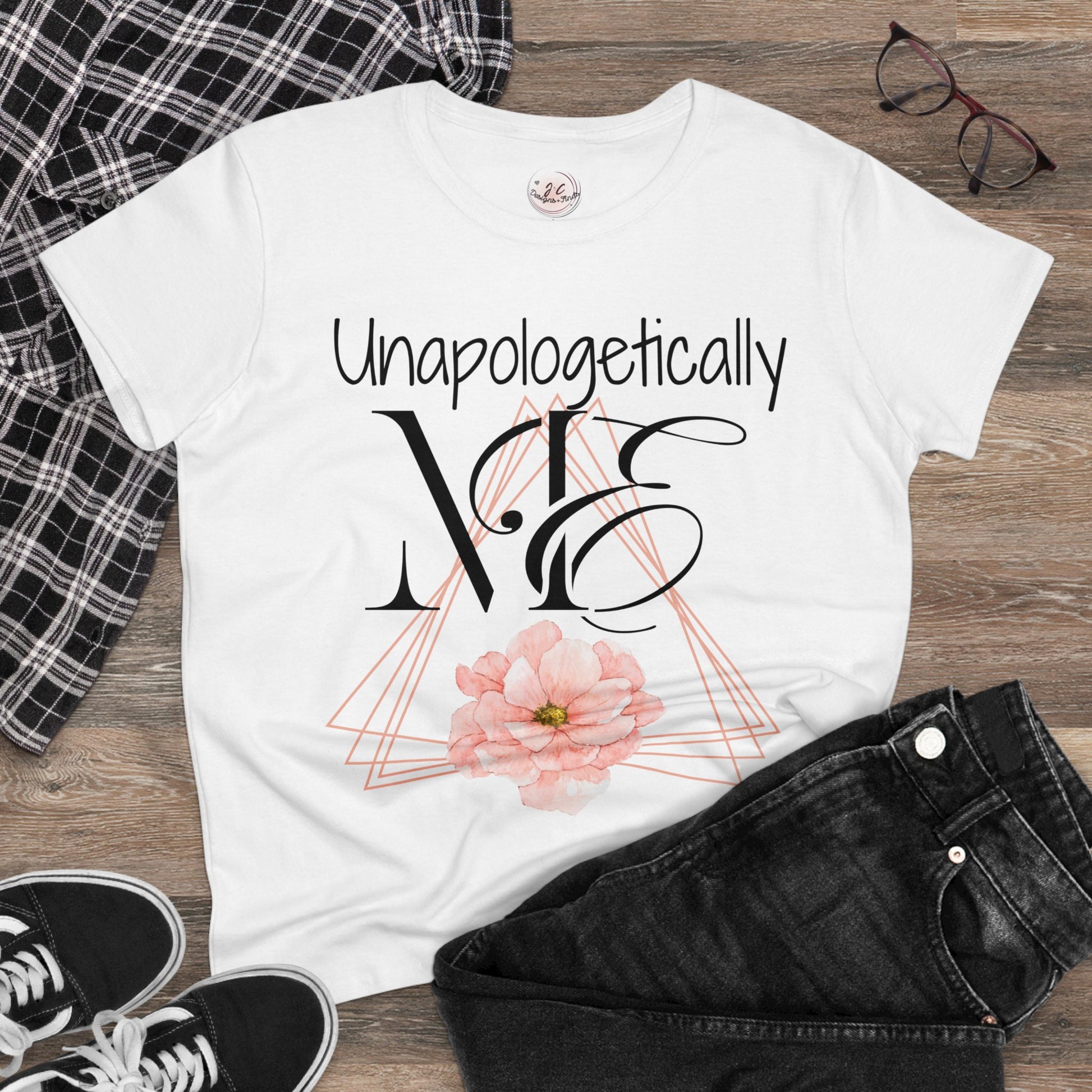 Women's Unapologetically Me Tshirt - Offset peach colored triangles with one solid peach flower in the bottom center - Unapologetically in handwritten font over ME in a large proper and then cursive wrapped around the M. Exuding all the confidence that women should have with a but of style and attitude. - white